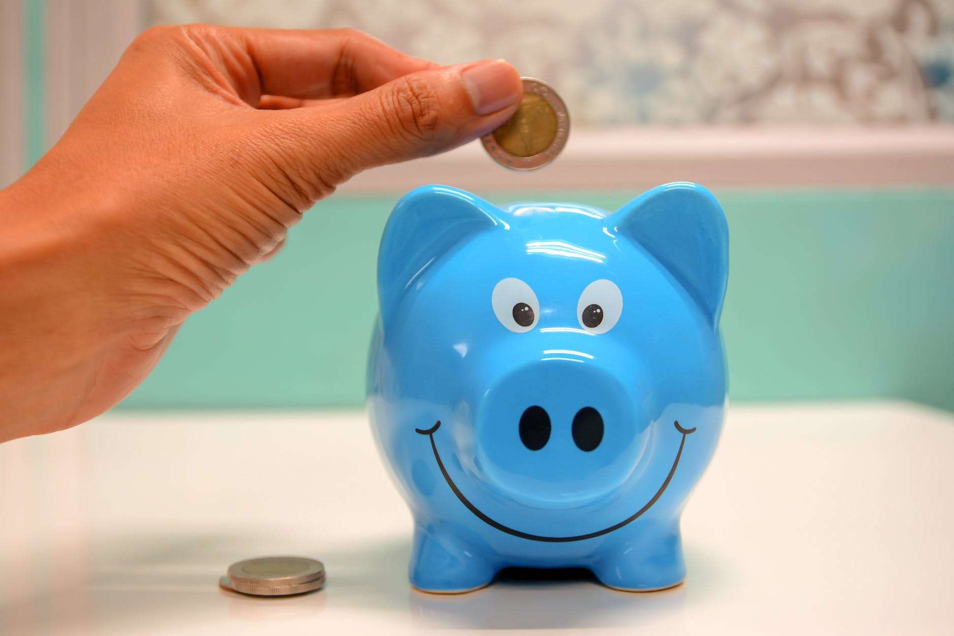 person putting a coin in a piggy bank