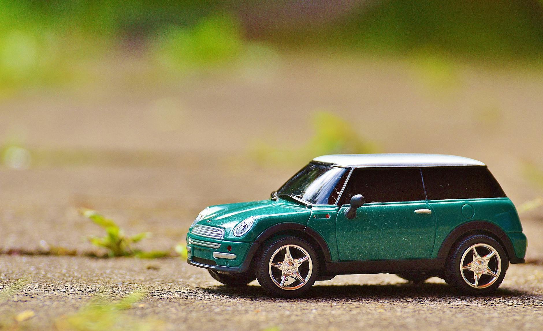 green scale model car on brown pavement - buying a car
