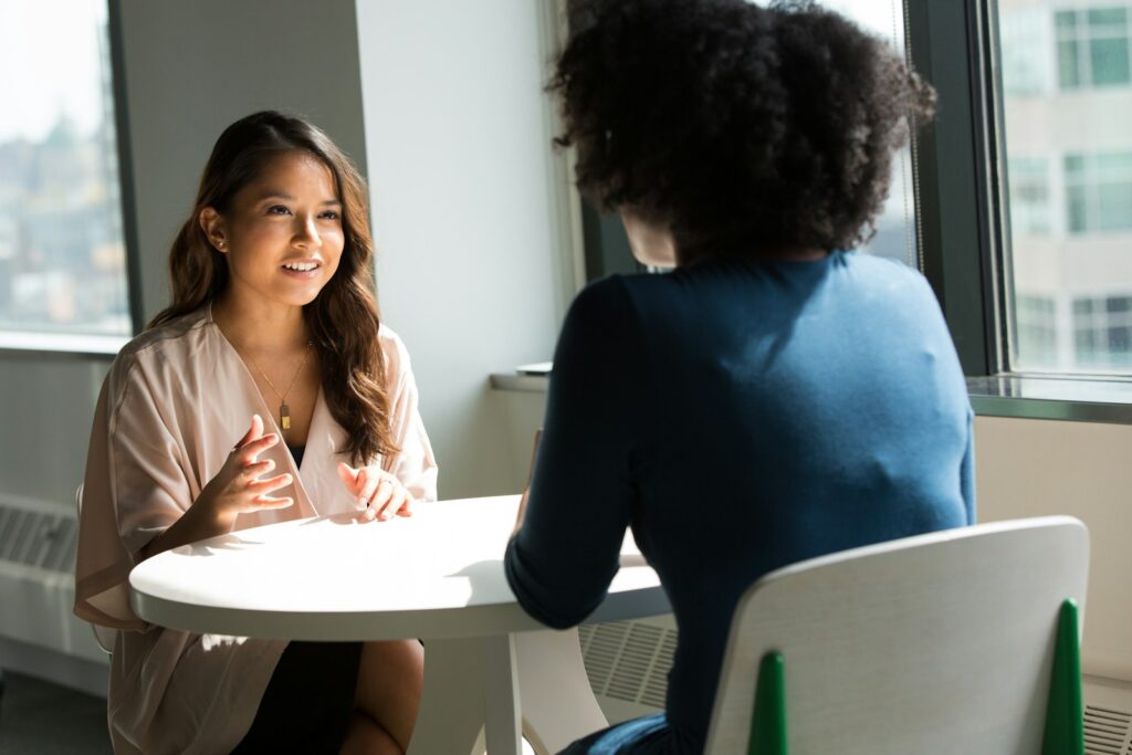 two women sitting on chair, discussing how the economy feels hopeless